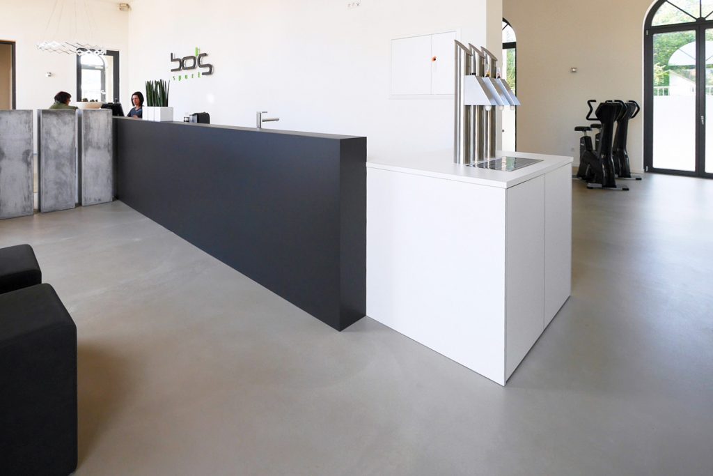 Empfangstheke / Anmeldung mit intergriertem Getränkespender in weiß und schwarz gehalten.