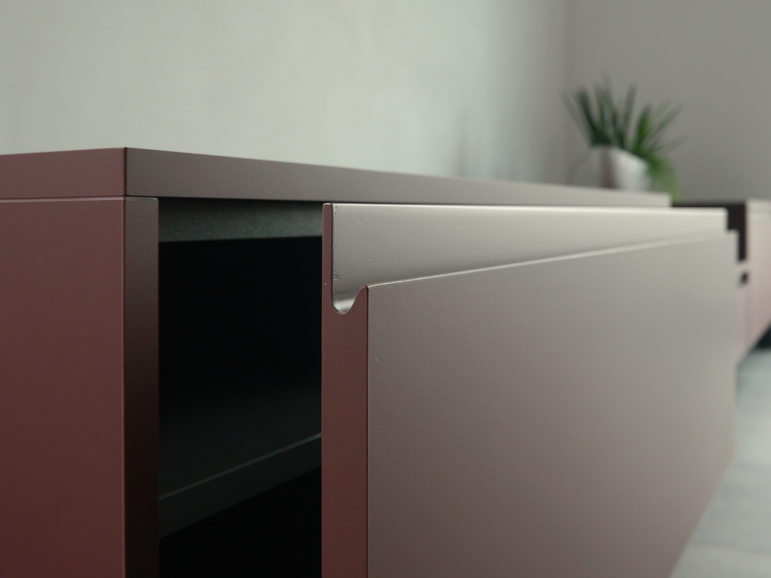 leicht geöffnete Schublade eines Lowboards, mit Griffmulde in weinrot