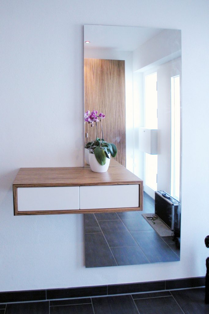 Spiegelelement mit angebautem Schubladenschränkchen aus Weißlack und Zebrano Furnier.