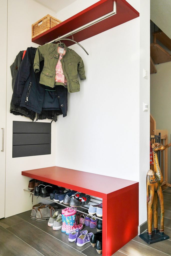 Garderobe und Sitzbank vor weißem Einbauschrank und drei anthrazit farbigen Schubladen mit griffloser Öffnungstechnik.