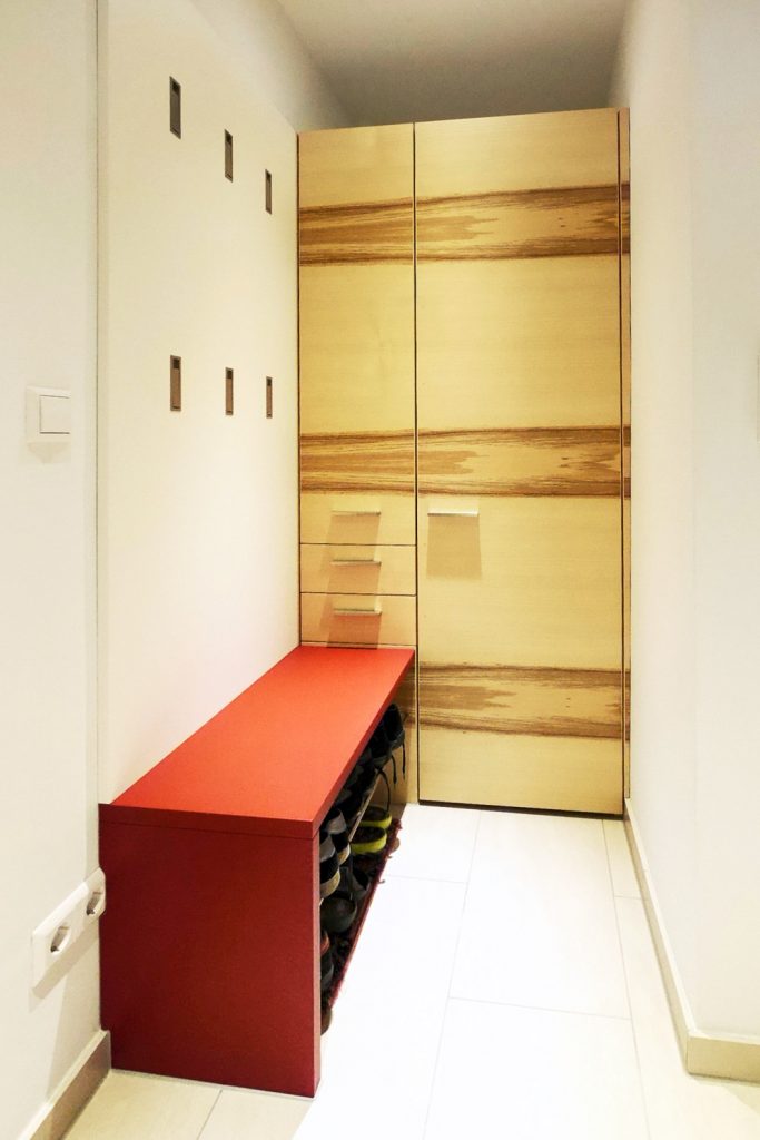 Einbauschrank aus Kernesche, horizontal furniert. Wandpanel mit sechs ausklappbaren Haken und Sitzbank im Vordergrund. HartmannWOHNfühlen, Ellhofen.