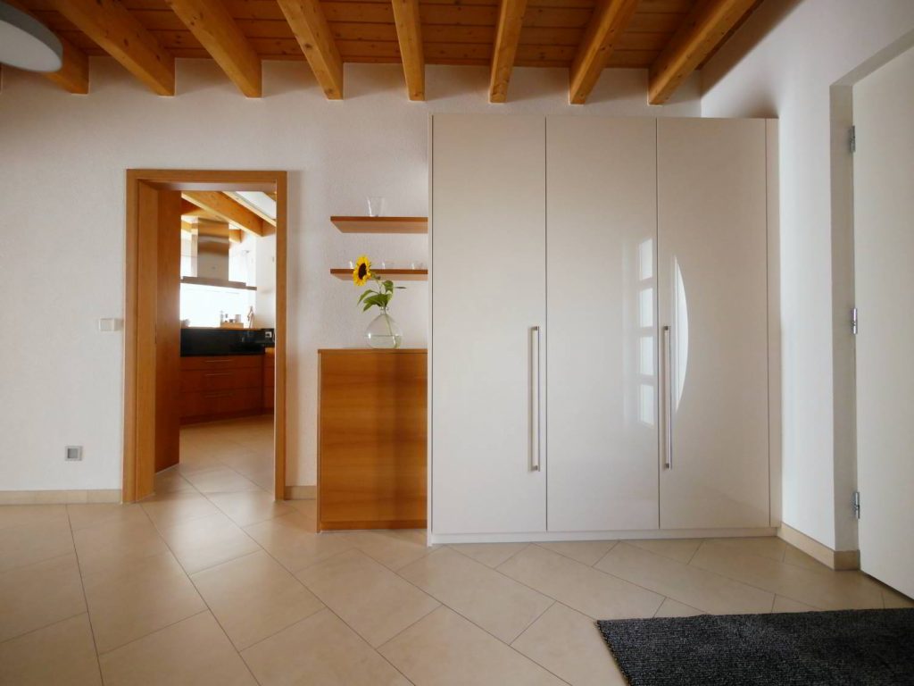 Garderobenschrank mit Hochglanzlack Fronten und europäischem Kirschbaum furnierten Akzenten, bietet viel Stauraum. Innenausbau Schreinerei Hartmann, Ellhofen.