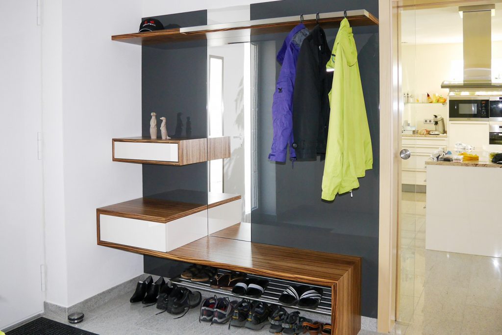 Garderobe aus Zebrano Furnier und Hochglanzlack weiß und anthrazit. Zwei Schubladen mit griffloser Öffnungstechnik und in die Rückwand eingelassenem Spiegel. Garderobenstange aus Edelstahl ist im Hutboden integriert. Schreinerei Hartmann, Ellhofen.
