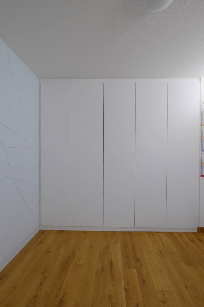 rehcts 5-türiger Einbauschrank in weiß gehalten. Auf der linken Wand die Wandverkleidung FAcet in IceBlue. Als Schallschluckendes Element in das Büro integriert