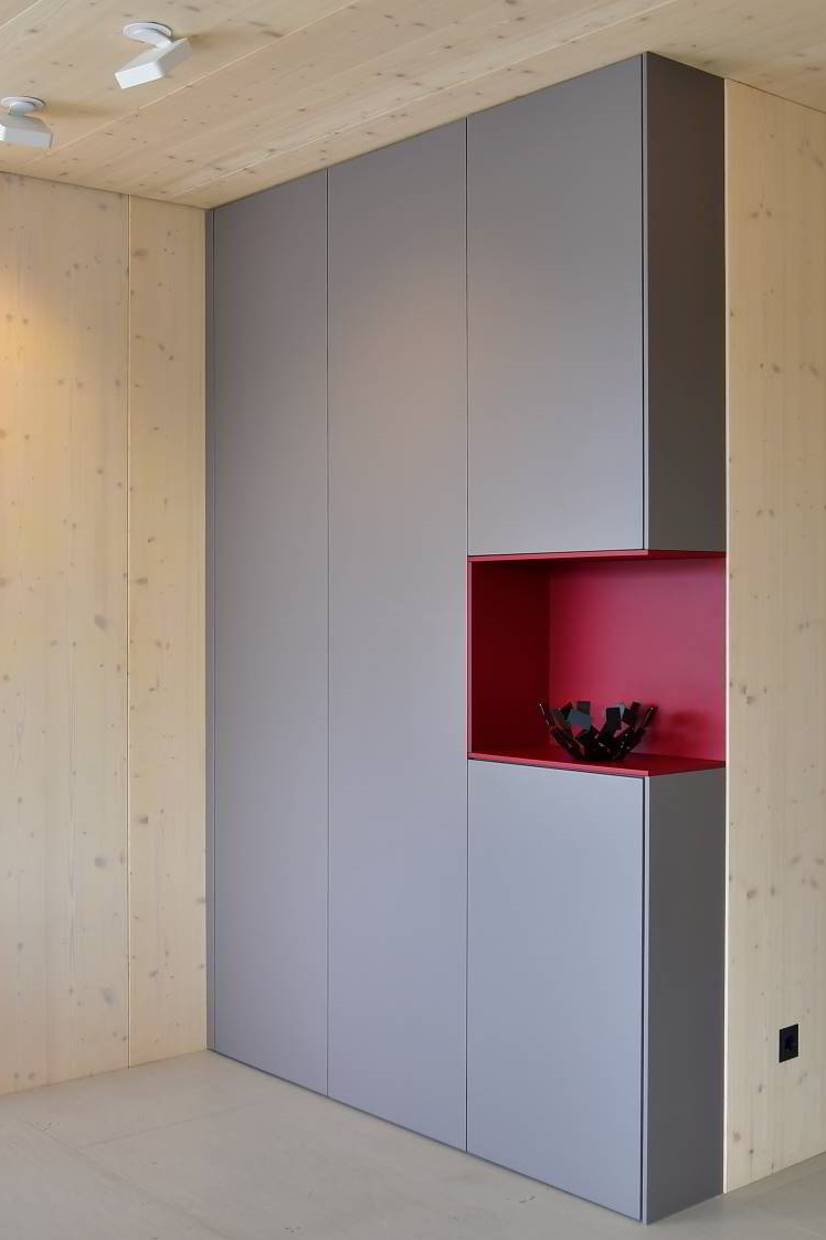 Raumhoher Schrank mit zwei Türen, rechts auch zwei Türen, in der Mitte eine weinrot lackierte Nische. Das Ganze als eine Ecklösung im offenen Wohnraum