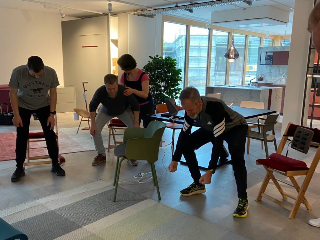 Das Team von Hartmann WOHNfühlen in der Möbel- Ausstellung beim Üben der Rückenentlastung Methode.