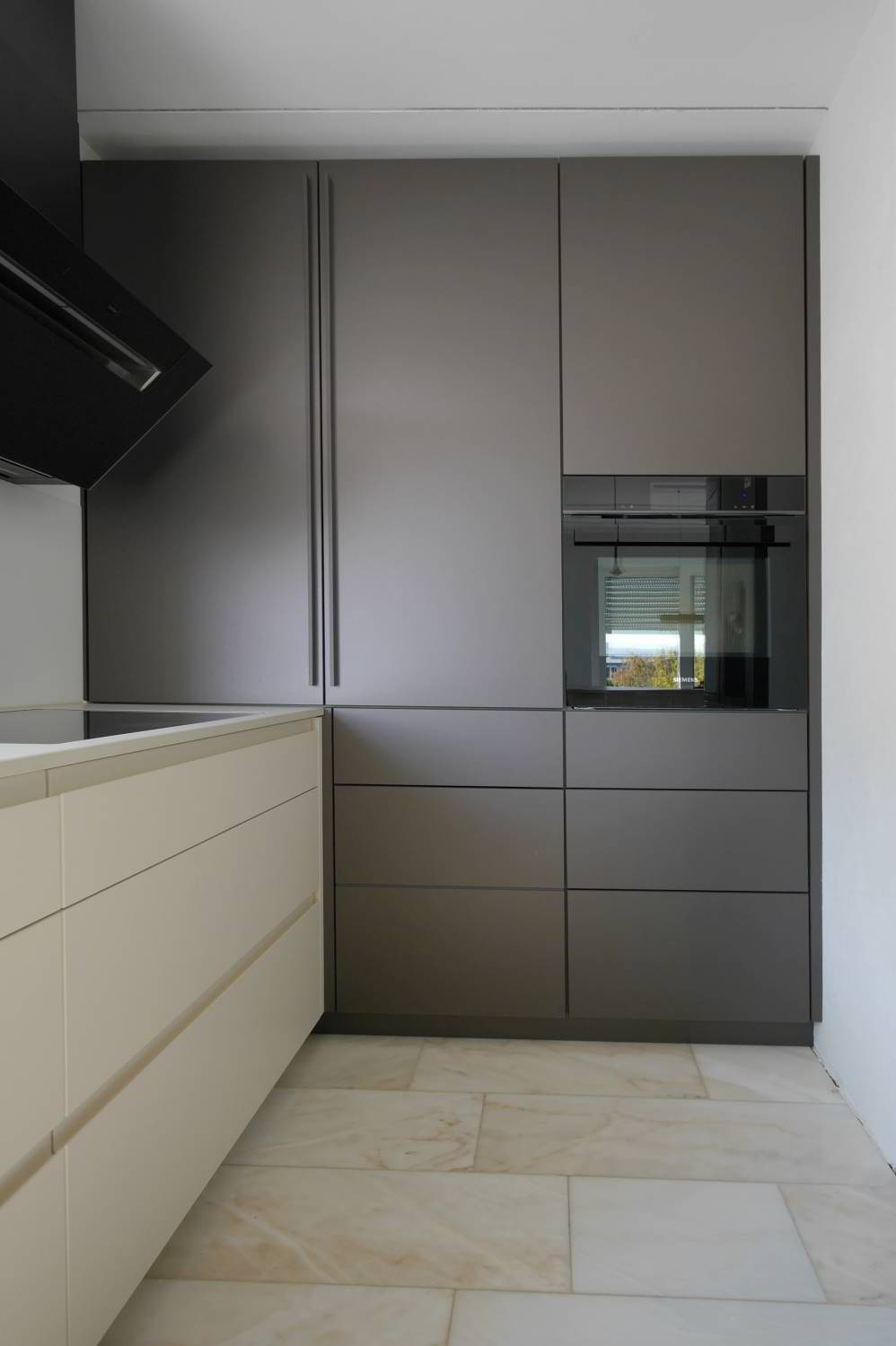 Einbauküche mit raumhohen Hochschränken in Rauvisio Glaslaminat Tericcio matt, links Unterschränke in hell mit Griffmulden