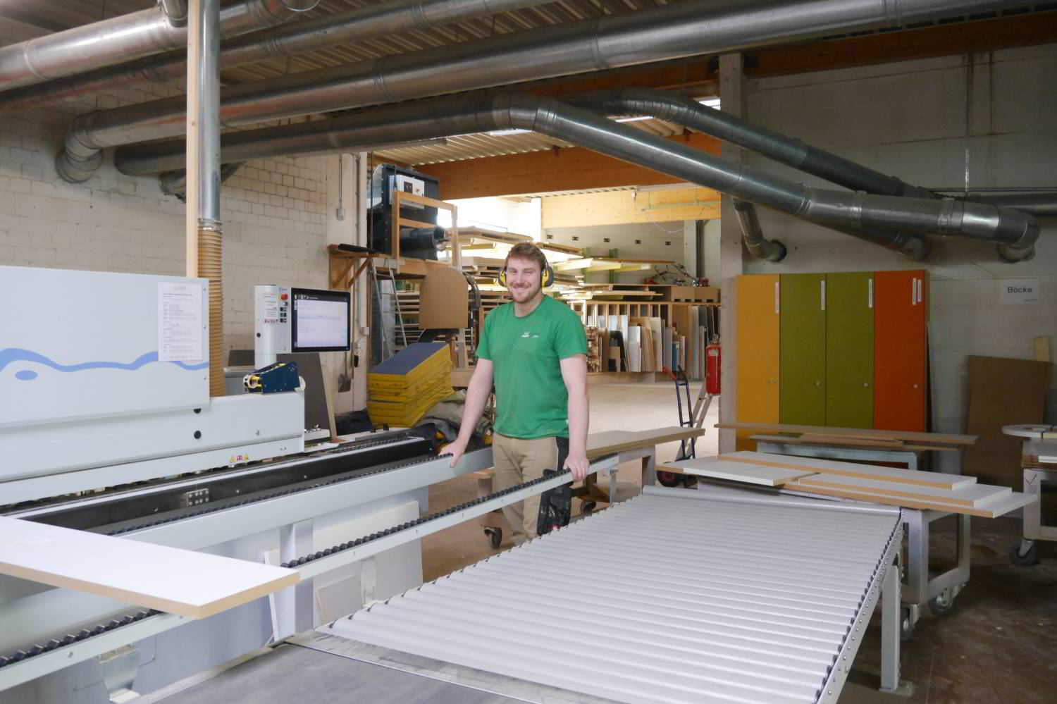 Kantenleimmaschine inder Produktion der Schreinerei Hartmann WOHNfühlen. Mit Teammitglied beim Kantenanleimen