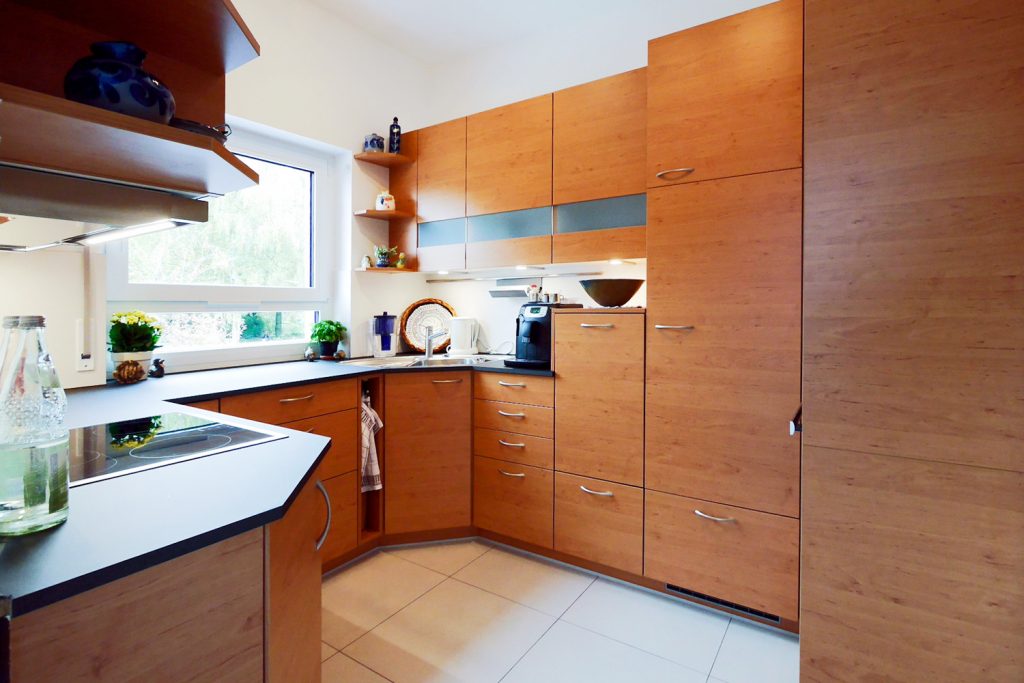 Holzeinbauküche mit Eckspüle und Metallgriffen. Arbeitsplatte anthrazit.