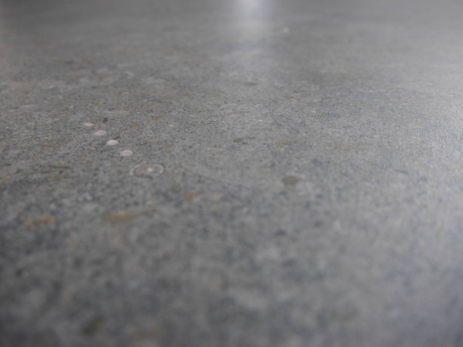 dunkelfraue Dekton Arbeitsplatte mit vier LED-Punkten zum Anzeigen der Restwärme. Daneben der eingefräste An- und Ausschalter.