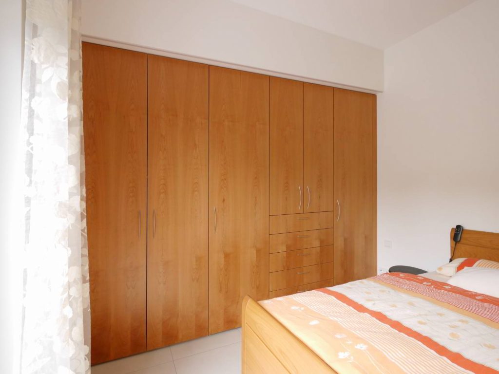 Geschlossener Schrank aus Kirschbaum Furnier, der Durchgang zur Ankleide ist nicht sichtbar.