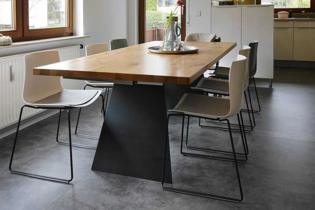 Esstisch mit Massivholzplatte und trapezförmigem Metallgestell von der Schreinerei Hartmann in Ellhofen.