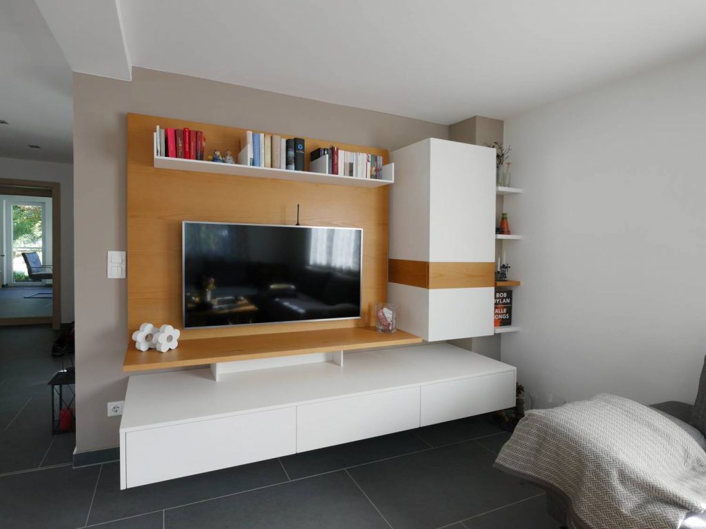 Wandhängendes Wohnzimmermöbel aus gebürstetem Fichte-Furnier und weiß lackierten Fronten. Rückwandpaneele mit Beleuchtung für angenehme Fernsehabende.