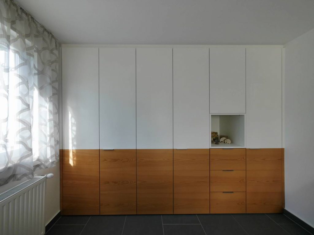 Schrankwand mit weißen und Holzelementen und offener Nische.