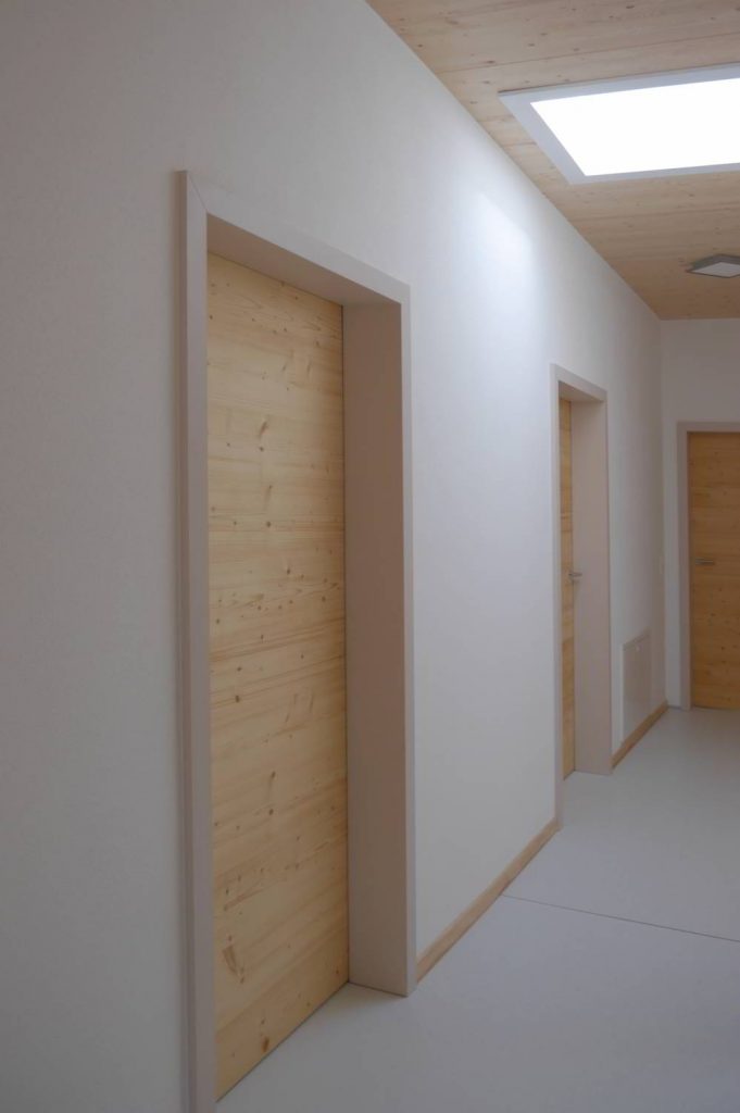 Flur mit weißen Wänden. Im Flur mehrere Türen abgehend. Zargen in einem hellen beige ton lackiert und Fichte Türeblätter.