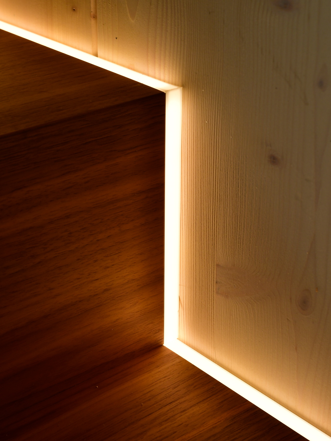 Eine durchdachte Schreiner Planung. Nussbaum furnierte Treppe mit eingearbeitetetm LED-Streifen, Holzwand im Anschluss