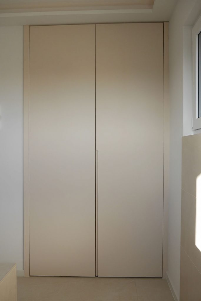 Eine Einrichtungsidee von der Schreinerei Hartmann WOHNfühlen in Ellhofen. Cremeweißer Einbauschrank mit zwei Türen und einer Griffmulde in Wand intetgriert.